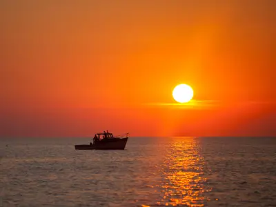 Beautiful deep orange sunset and a boat is out on the horizon
